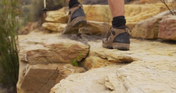 Füße Männlicher Überlebenskünstler Die Wanderschuhen Und Mit Stöcken Über Felsiges — Stockvideo