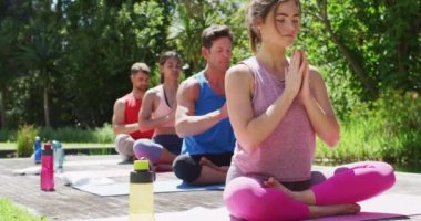 Çeşitli erkek ve kadın grupları yoga yapıyor. Güneşli parkta gözleri kapalı oturuyorlar. fitness, sağlıklı hobiler ve açık havada aktif yaşam tarzı.