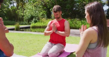 Mutlu çeşitli yoga grupları güneşli parkta minderlerin üzerinde diz çökerek poz veriyor. fitness, sağlıklı hobiler ve açık havada aktif yaşam tarzı.