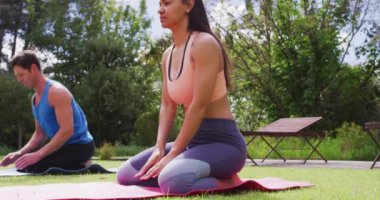 Yoga yapan çeşitli erkek ve kadın grupları parkta minderlerin üzerinde diz çökerek poz veriyorlar. fitness, sağlıklı hobiler ve açık havada aktif yaşam tarzı.