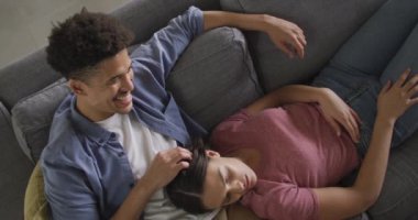 Oturma odasındaki kanepede oturup kucaklaşan mutlu çift. Kaliteli zaman, evde birlikte dinlenmek..