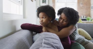 Üzgün Afro-Amerikan anne ve kızı kanepede oturup kucaklaşıyorlar. evde aile hayatı ve kaliteli aile zamanı.