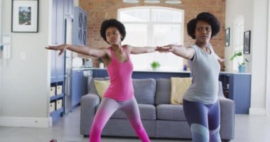 Mutlu Afro-Amerikan anne ve kızı oturma odasında yoga yapıyor, esniyor. evde aile hayatı ve kaliteli aile zamanı.