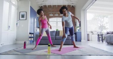 Mutlu Afro-Amerikan anne ve kızı oturma odasında yoga yapıyor, esniyor. evde aile hayatı ve kaliteli aile zamanı.