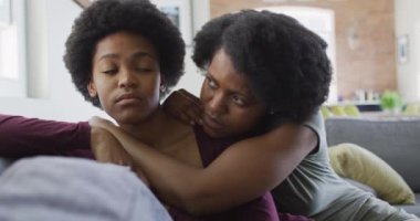 Üzgün Afro-Amerikan anne ve kızı kanepede oturup kucaklaşıyorlar. evde aile hayatı ve kaliteli aile zamanı.