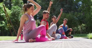 Çeşitli erkek ve kadın grupları yoga yapıyor. Güneşli parkta gözleri kapalı oturuyorlar. fitness, sağlıklı hobiler ve açık havada aktif yaşam tarzı.