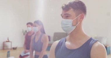 Çeşitli erkek ve kadın maskeli gruplar yoga dersinde hasırların üzerine diz çöküp eğitmeni dinliyorlar. Zindelik, sağlıklı hobiler ve aktif yaşam tarzı covid 19 salgını sırasında.