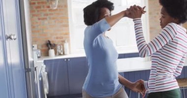 Mutlu Afro-Amerikan anne ve kızı mutfakta birlikte dans ediyor. evde aile hayatı ve kaliteli aile zamanı.