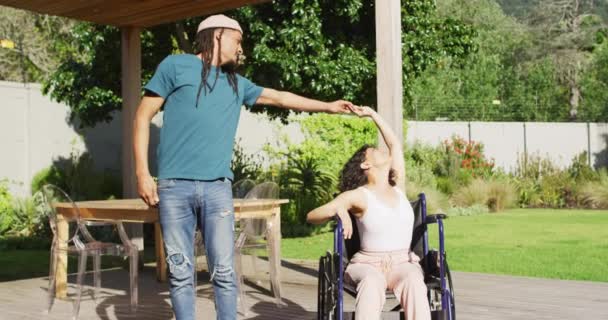 庭のテラスで踊る幸せな出産のカップル 車椅子に座っている女性 ドレッドロックを持つ男 身体障害者の健康と国内生活 — ストック動画