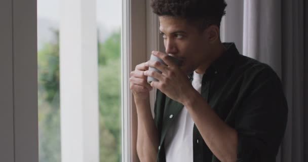 有思想的鸟人从窗户往外看 喝咖啡 高质量的时间 在家里放松 — 图库视频影像