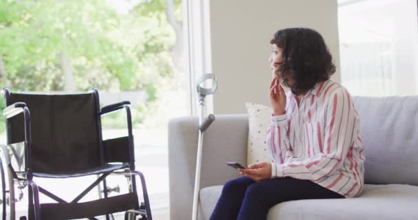 Přemýšlivá Biracial Invalidní Žena Pomocí Smartphonu Obývacím Pokoji Berle Invalidní — Stock video