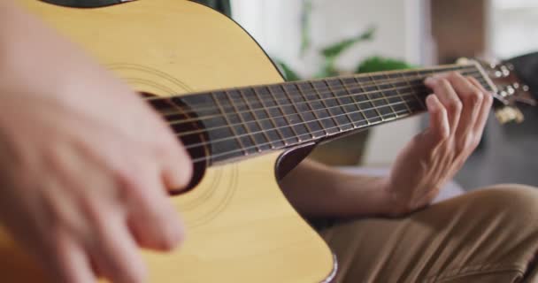 把坐在客厅沙发上弹奏吉他手关起来 高质量的时间 在家里放松 — 图库视频影像