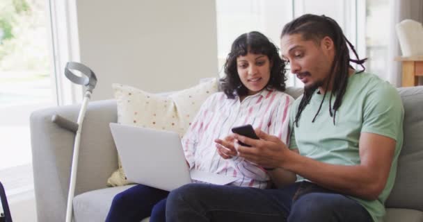 Gelukkige Biraciale Paar Woonkamer Met Behulp Van Laptop Smartphone Met — Stockvideo