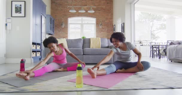 幸せなアフリカ系アメリカ人の母親と娘がリビングルームでヨガをし ストレッチ 家庭での家庭生活と質の高い家庭生活 — ストック動画