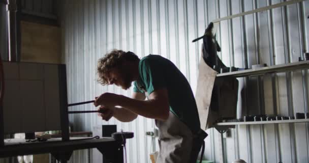 白人男性铁匠在窑炉里拿着热金属工具 车间里有钳子 小生意和锻造铁匠的工艺 — 图库视频影像
