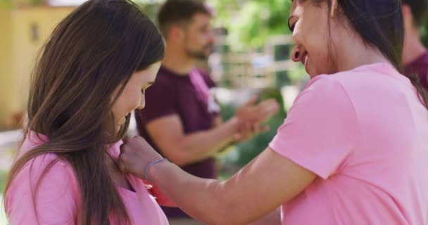 Två Glada Olika Kvinnor Fästa Bröstcancer Band Till Shirt Prata — Stockvideo