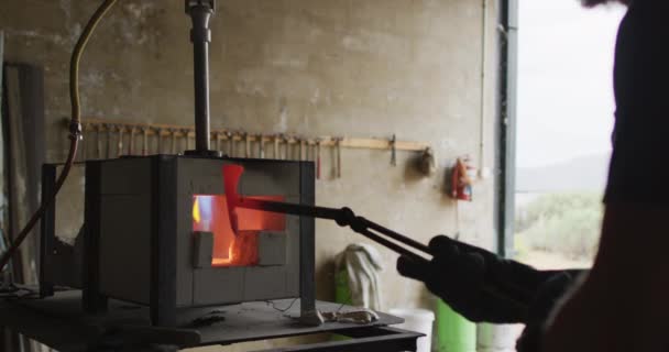 ワークショップでは 窯の中で熱い金属工具を持つ白人男性の鍛冶屋 鍛冶屋での小さなビジネスと職人技が — ストック動画
