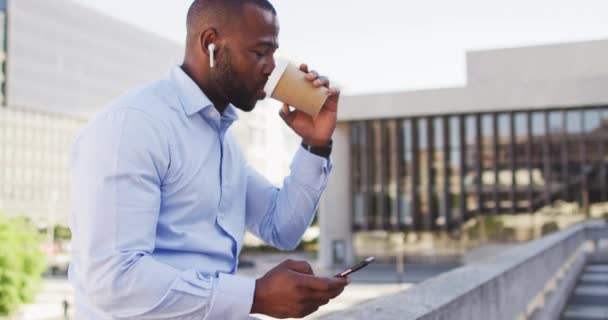 城市里的非裔美国人站在阳光下 喝咖啡 用智能手机 城市里到处都是数字游牧民族 — 图库视频影像
