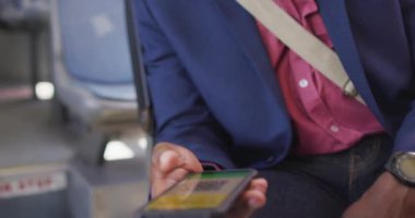 Otobüste pasaport taşıyan akıllı telefon kullanan maskeli Afro-Amerikan bir adam. Şehir merkezinde, covid 19 salgını sırasında..