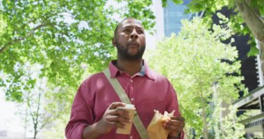 Afrika kökenli Amerikalı bir adam kahve içiyor, yemek yiyor ve şehirde yürüyor. Şehirdeki hayat tarzı, hayat devam ediyor..