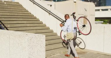 Şehirde bisiklet taşıyan Afro-Amerikan bir adamın arka görüntüsü. Şehirdeki hayat tarzı, hayat devam ediyor..