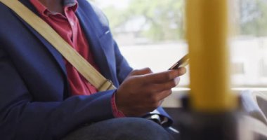 Şehirde yüzü olan, otobüste akıllı telefon kullanan Afro-Amerikan bir adamın elleri. Dijital göçebe covid 19 salgını sırasında şehirde dolanıyor..