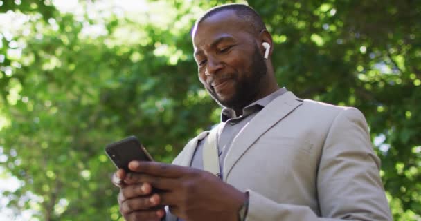 Şehirde Kulaklık Takan Akıllı Telefon Kullanan Mutlu Bir Afrikalı Amerikalı — Stok video