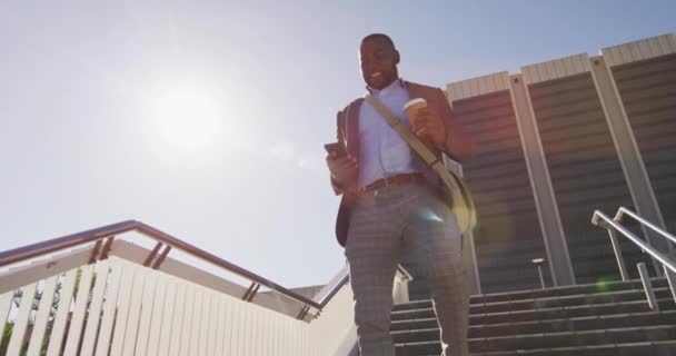 Hombre Afroamericano Ciudad Caminando Abajo Sosteniendo Café Usando Teléfono Inteligente — Vídeo de stock