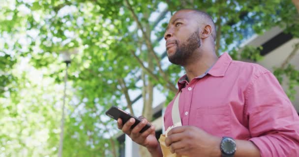 Αφροαμερικάνος Τρώει Και Χρησιμοποιεί Smartphone Στην Πόλη Ψηφιακός Νομάδας Κινήσει — Αρχείο Βίντεο