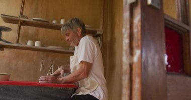 Önlük giyip atölyesinde çömlek yapan kıdemli beyaz adam. aktif emeklilik, hobiler ve yaratıcılık.