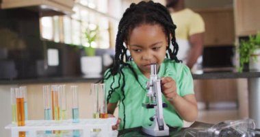 Mikroskop kullanarak, evde bilimsel deneyler yaparak odaklanmış Afrikalı Amerikalı kız. Evde ailece güzel vakit geçiririz..