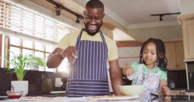 Mutlu Afro-Amerikan baba ve kızı mutfakta pizza hazırlıyor. Kaliteli aile zamanı, evde birlikte yemek pişirmek..