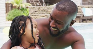 Mutlu Afro-Amerikan baba ve kızının yüzme havuzunda eğlenirken portresi. Evde ve bahçede birlikte güzel vakit geçiririz..