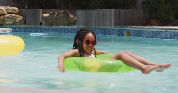 Glückliches Afrikanisches Amerikanisches Mädchen Mit Sonnenbrille Das Auf Einem Aufblasbaren — Stockvideo