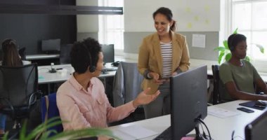 İki farklı iş kadını masa başı bilgisayarında iş tartışıyor. Bağımsız yaratıcı iş, modern bir ofiste çalışmak..