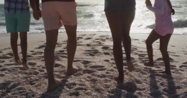 İspanyol anne, baba, oğul ve kızın el ele tutuşup kumsalda yürümelerini. Aile tatilleri, boş zaman ve birliktelik.