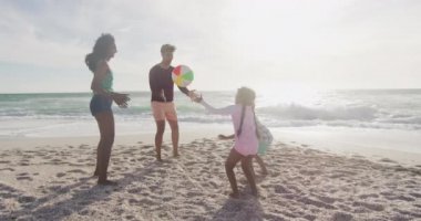 Mutlu İspanyol anne, baba, oğul ve kız sahilde top oynuyorlar. Aile tatilleri, boş zaman ve birliktelik..