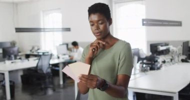 Odaklanmış Afro-Amerikan iş kadını ofisteki en iyi seçeneğe karar veriyor. Bağımsız yaratıcı iş, modern bir ofiste çalışmak..