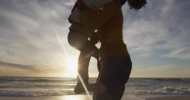 İspanyol annenin kızını sırtında taşıdığı ve sahilde gün batımını izlediği sahne. Aile tatilleri, boş zaman, birliktelik ve dışarıda zaman geçirmek..