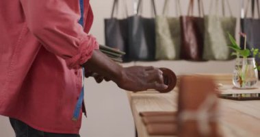 Deri atölyesinde cüzdan düzenleyen Afrikalı Amerikalı zanaatkarın elleri. Bağımsız küçük işletmeci iş başında.