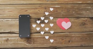 Sevgililer gününde tahta arka planda kağıt kalpler ve akıllı telefon. Sevgililer günü, aşk ve kutlama konsepti..