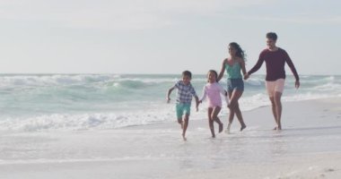 Mutlu İspanyol anne, baba, oğul ve kız sahilde koşuyor. Aile tatilleri, boş zaman ve birliktelik..