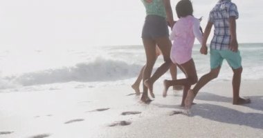 İspanyol anne, baba, oğul ve kızın el ele tutuşup kumsalda yürümelerini. Aile tatilleri, boş zaman ve birliktelik.