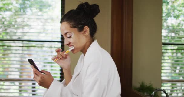 Mulher Biracial Feliz Roupão Escovando Dentes Usando Smartphone Beleza Bem — Vídeo de Stock