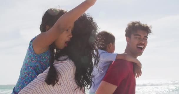 Happy Hispanic Parents Carrying Children Piggyback Walking Beach Family Holidays — Stock Video