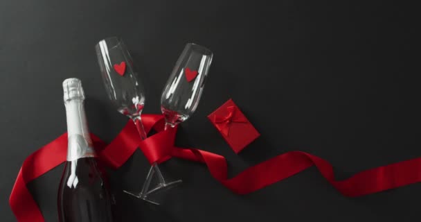 バレンタインデーにプレゼントとレッドリボンのシャンパングラスとボトル バレンタインデー愛とお祝いのコンセプト — ストック動画