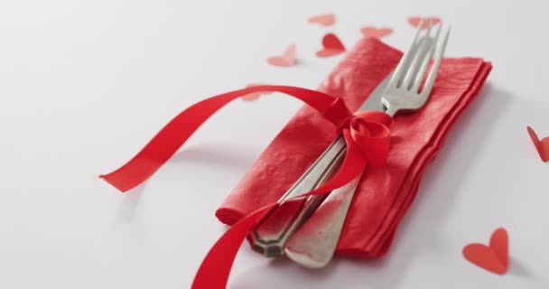 Příbory a červená stuha s papírovými srdíčky na růžovém pozadí na Valentýna. Valentýn, koncept lásky a oslav.