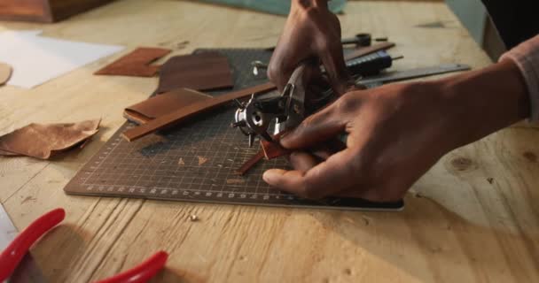 Ręce Afrykańskiego Rzemieślnika Używającego Narzędzi Zrobienia Dziury Warsztacie Skórzanym Niezależny — Wideo stockowe