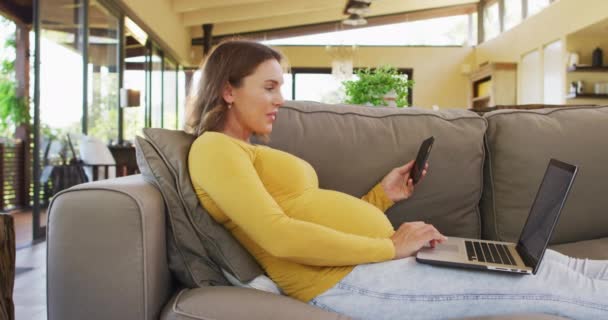 Szczęśliwa Kobieta Ciąży Siedząca Fotelu Używająca Smartfona Laptopa Ciąża Macierzyństwo — Wideo stockowe