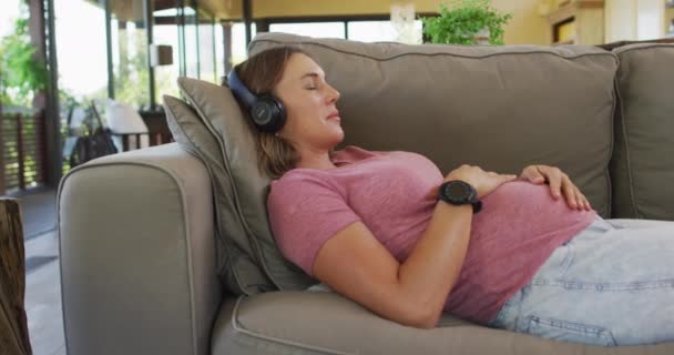 Mujer Embarazada Caucásica Relajada Tumbada Sofá Escuchando Música Embarazo Maternidad — Vídeo de stock